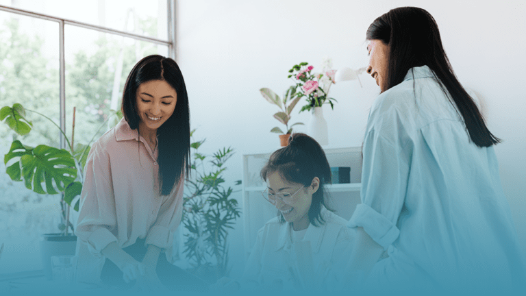 three young women sit around a computer discovering five proven strategies to boost workplace productivity.