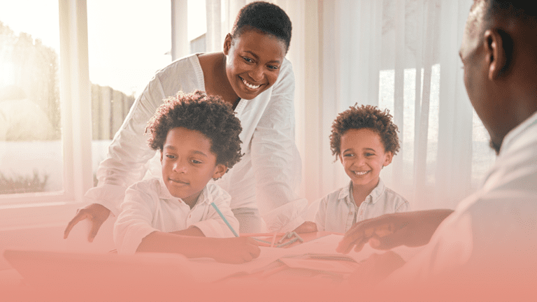 smiling family sits around a table while the parents help their kids cope with stress