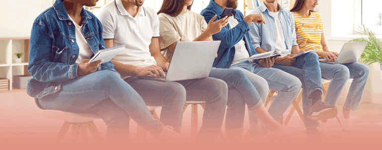 group of people sit with laptops and notebooks while learning about the benefits of setting personal development goals.
