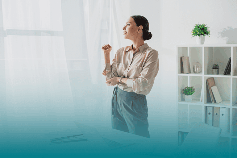 a young professional woman stands in a modern office looking out the window reflecting on how to strengthen your response to change.