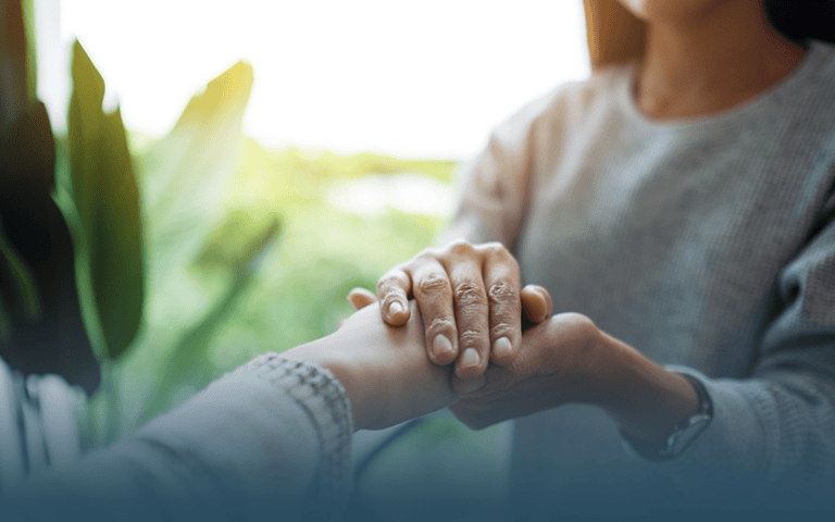 a caregiver holding the hand of their loved one discussing hope and resilience