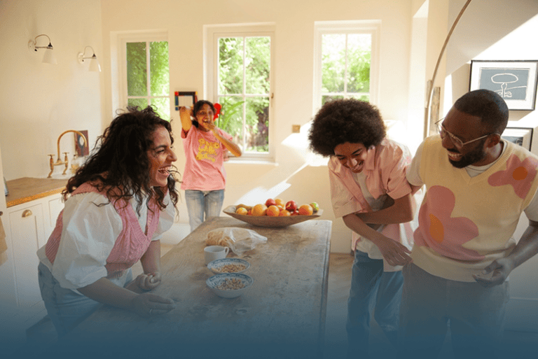 Family laughs and plays together around the kitchen counter, boosting their collective energy.