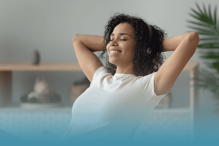 Woman leans back at her desk in satisfaction, because she is feeling energized.